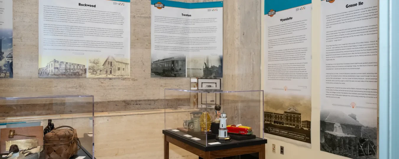 Exhibit room with historical displays, text panels, and artifacts on tables.