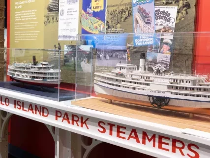 Scale models of steamboats in glass cases on display, with informational posters behind them.