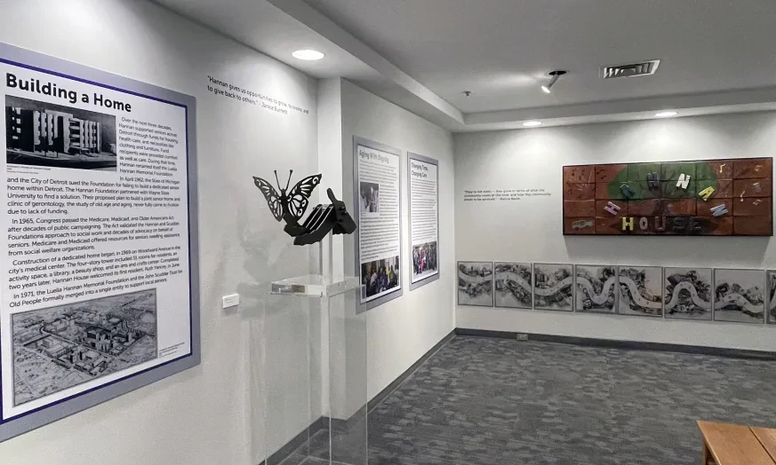 Museum gallery with informational panels, a sculpture, and a colorful mural on the wall.