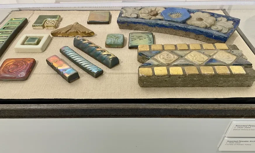 Decorative ceramic tiles and borders displayed in a glass case.