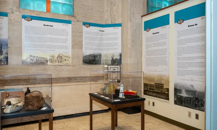 Exhibit room with historical displays, text panels, and artifacts on tables.
