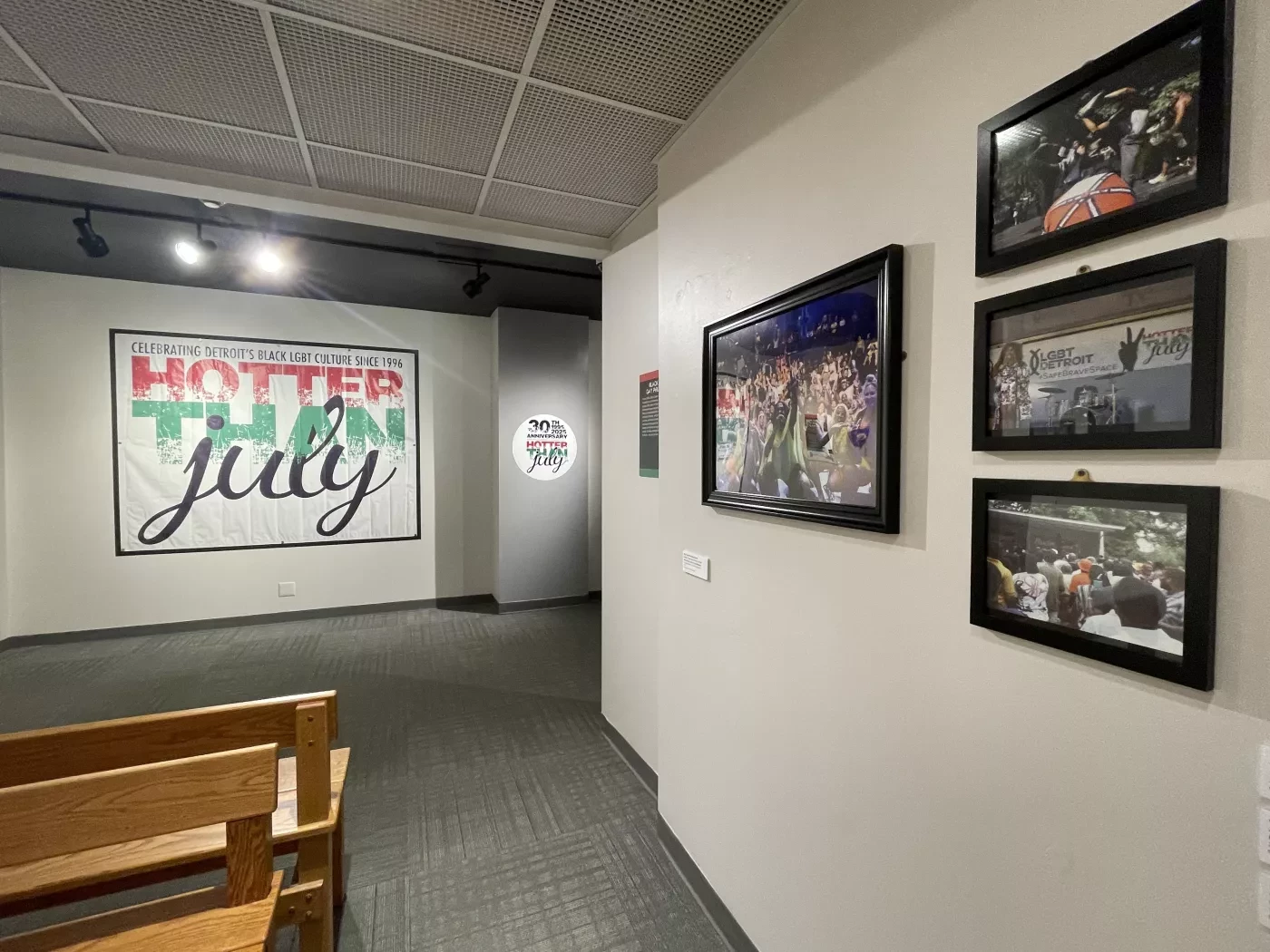 Hallway with framed photos on walls, large banner reading "Hotter Than July," and a wooden bench.