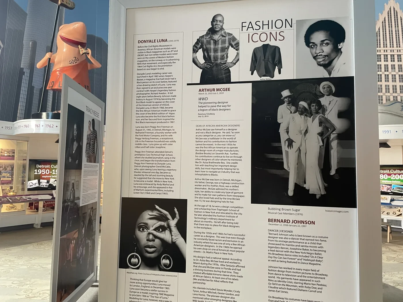 Museum display featuring black and white photographs and text about fashion icons.