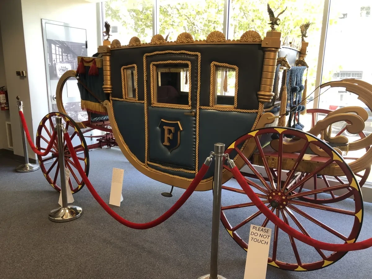 Ornate blue stagecoach with large red wheels on display in a museum setting.