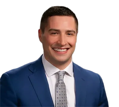 Smiling man in a blue suit and gray tie against a plain background.