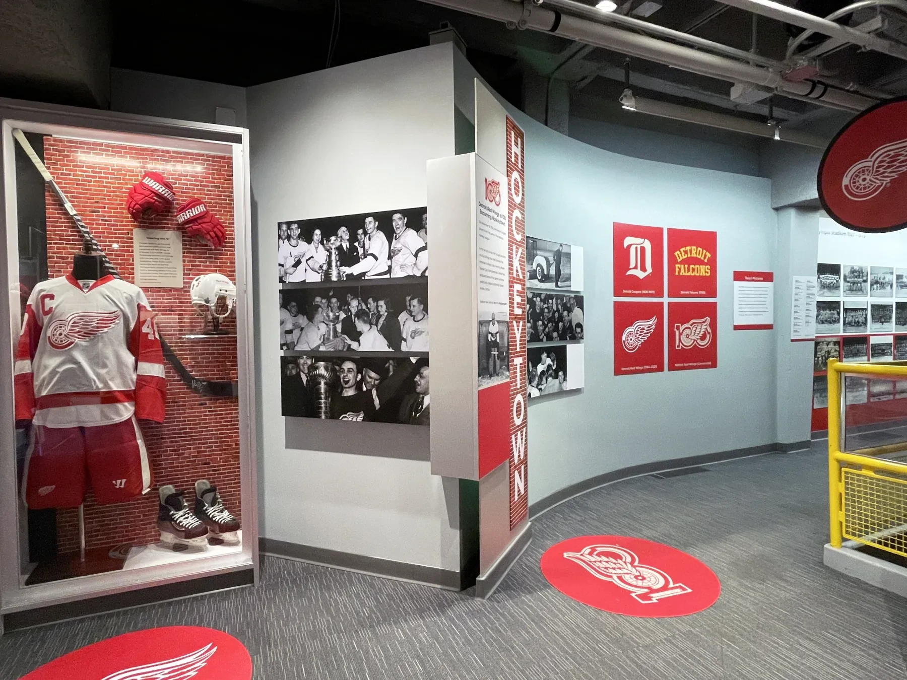 Hockey exhibit with vintage uniforms, photos, and team logos in a museum setting.